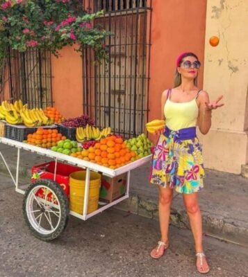 Turistas disfrutando de un colorido puesto de frutas en un tour por la ciudad de Cartagena, resaltando la vibrante atmósfera urbana.