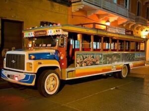 Colorida chiva rumbera estacionada en una calle de Cartagena por la noche, invitando a los visitantes a disfrutar de un tour único.