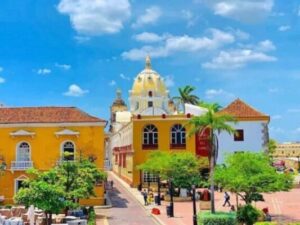 Vista panorámica de Cartagena con edificios coloniales coloridos y una cúpula amarilla destacando bajo un cielo azul, perfecta para un city tour.