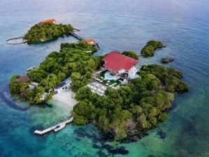 Vista aérea de un resort tropical en una isla con techo rojo y un bote blanco cerca